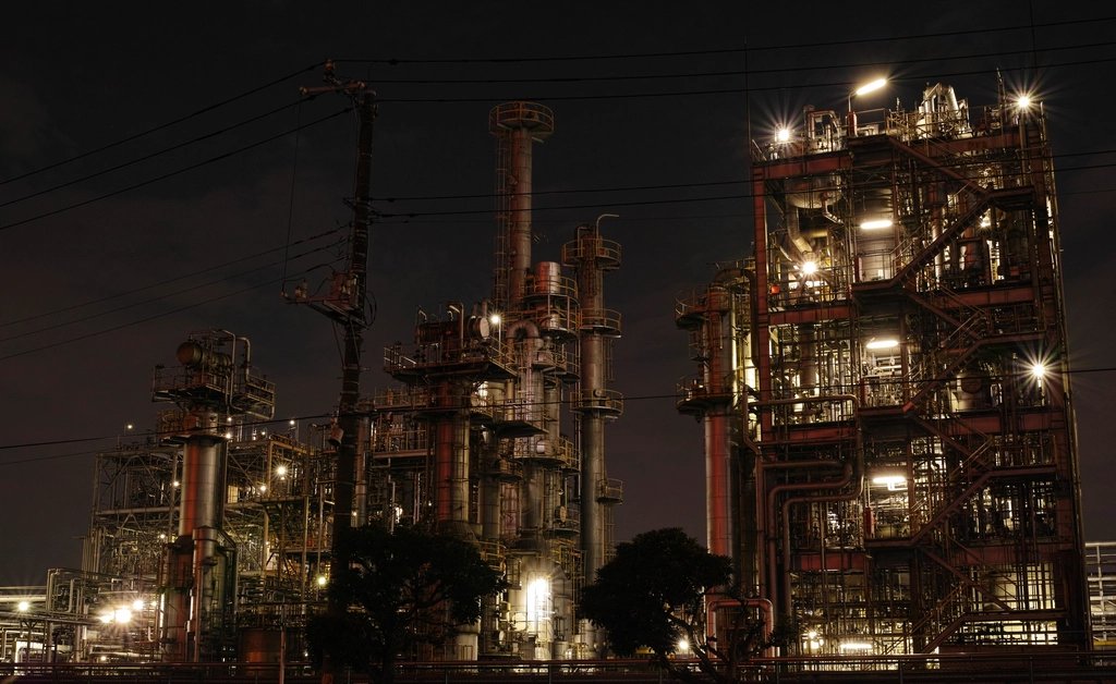 Refinery towers and pipework lit up against the night sky